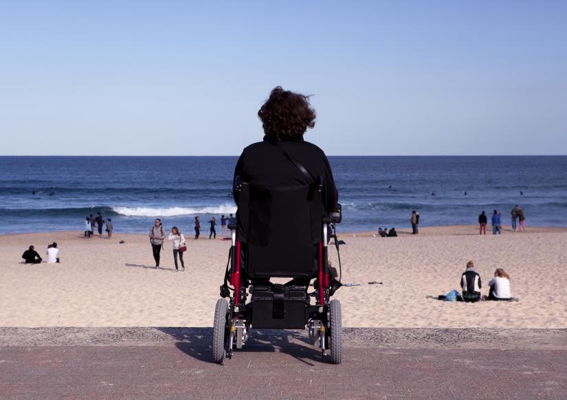 Women in powerchair on promenade looking at the beach
