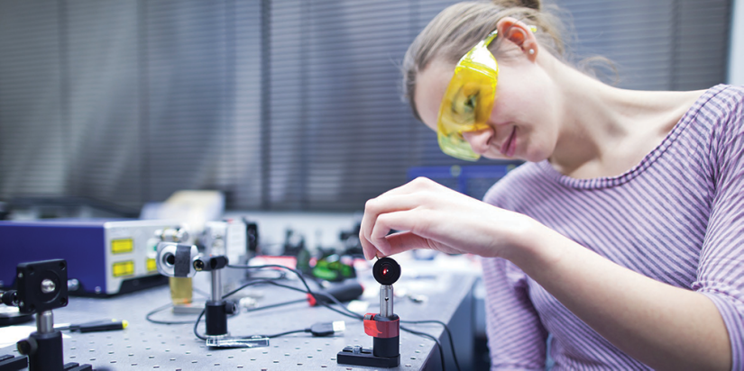 female researcher with yellow safety glasses positioning quantum hardware