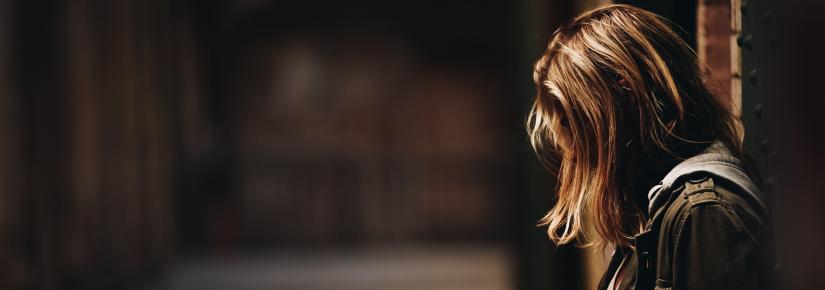 Woman in a dark hallway hangs her head.