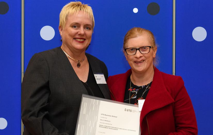 Two women smiling and looking at the camera while holding a certificate