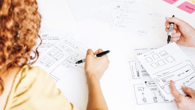People sketching wireframe designs with pen and paper