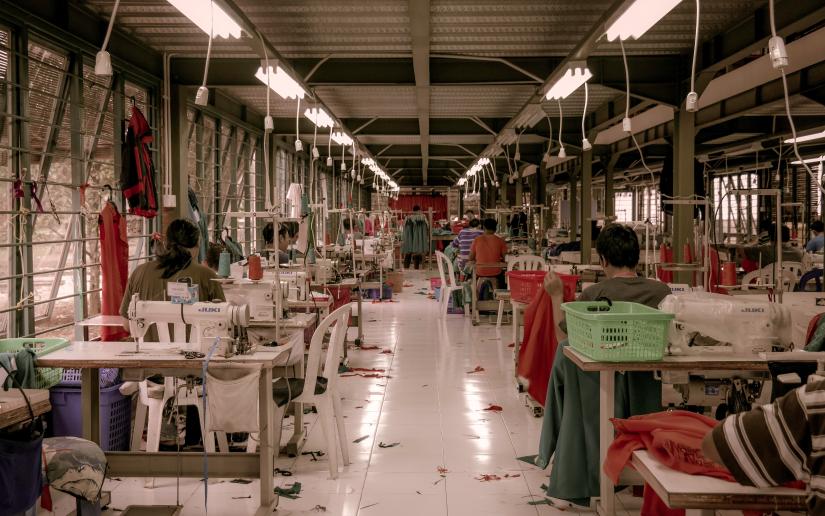 garment workers sitting at sewing machines in a factory.