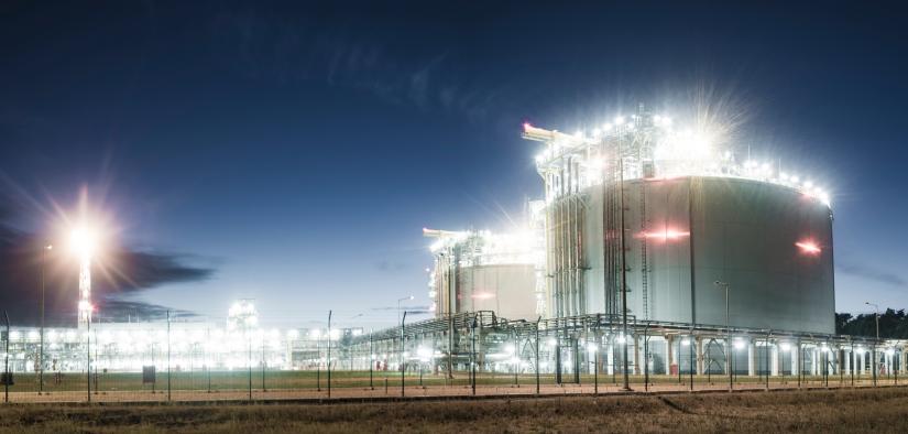 A liquefied natural gas storage facility at night with two large storage tanks in the foreground