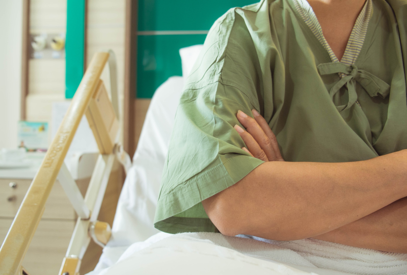 Hospital patient sitting in a hospital bed with their arms crossed