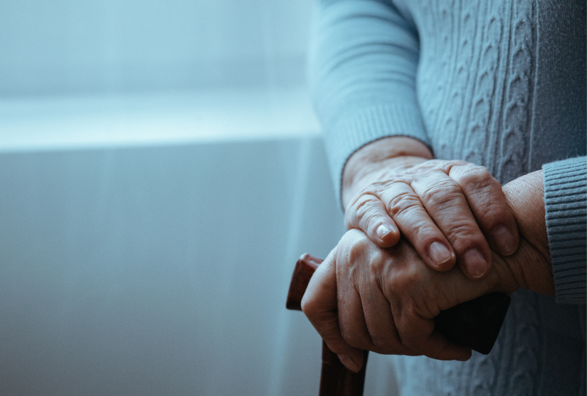 Elderly woman with her hands holding a walking stick