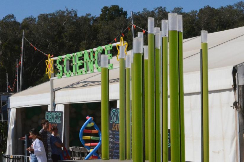 Science word above a white tent, next to the tent are long tubes filled with green algae 