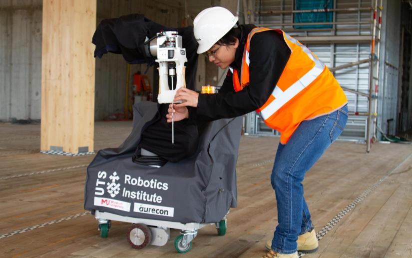 UTS researcher Dinh Dang Khoa Le fits a screw into QUENDA-BOT's arm while trialling the technology on a construction site.  Photo supplied by Murdoch University.