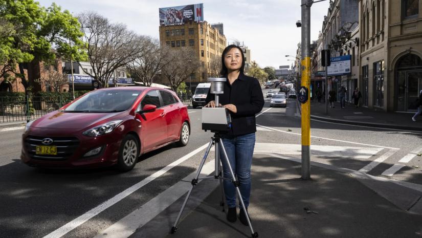 woman with air monitoring device standing beside road