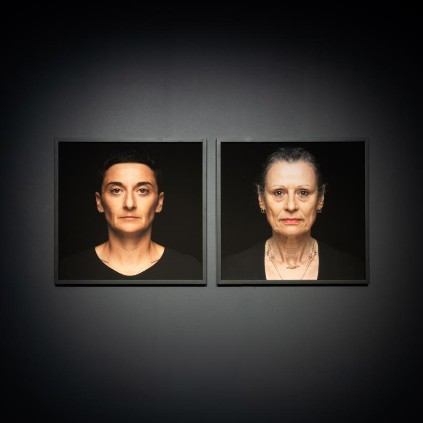 Two portraits hung on a black wall 