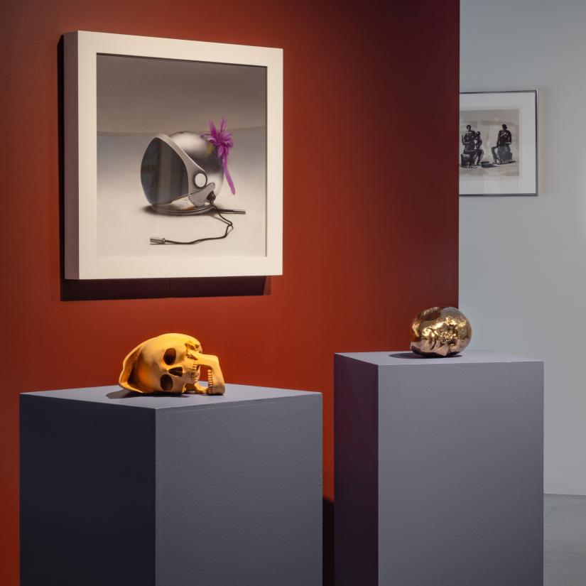 Two skulls on plinths and a painting on a wall
