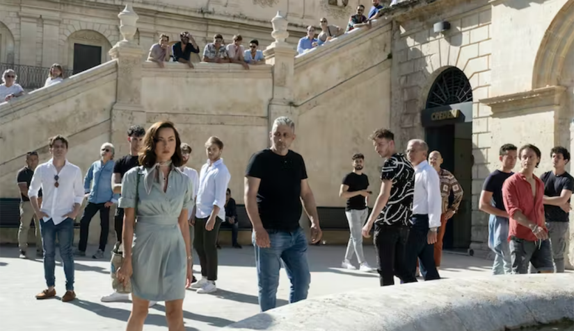 A scene from The White Lotus in which Aubrey Plaza is surrounded by a crowd of men in Noto, Italy