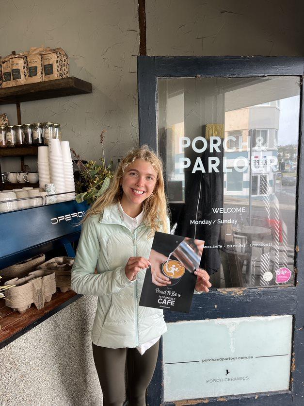 photo of Julianne holding a menu of the cafe she volunteered at
