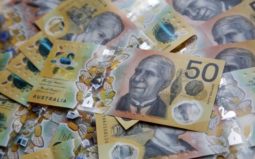 a pile of Australian bank notes with a $50 note on the top