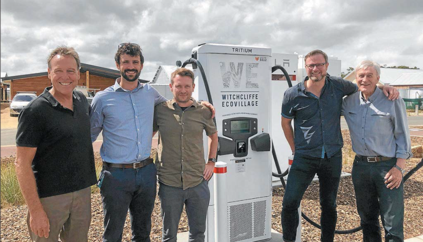 Five men stand with an EV charging station