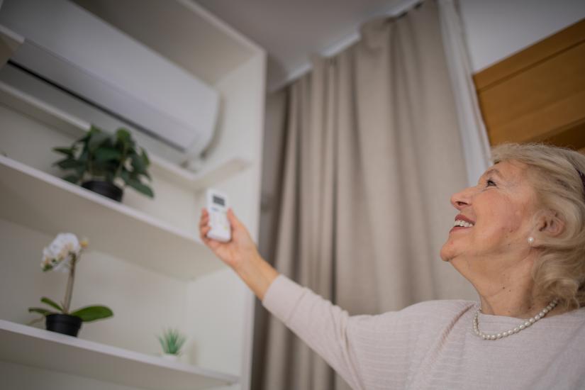 Elderly women turning air conditioning on