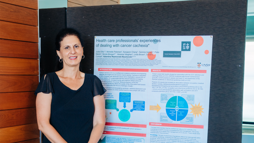 Dr Tina Naumovski standing in front of her poster at the PaCCSC & CST Annual Research Forum 2023