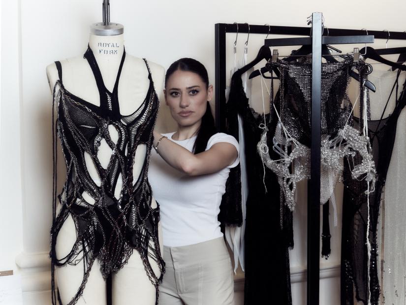Caroline Reznik stands next to a fashion mannequin and rack of clothes.