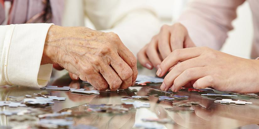 Two sets of hands doing a puzzle.