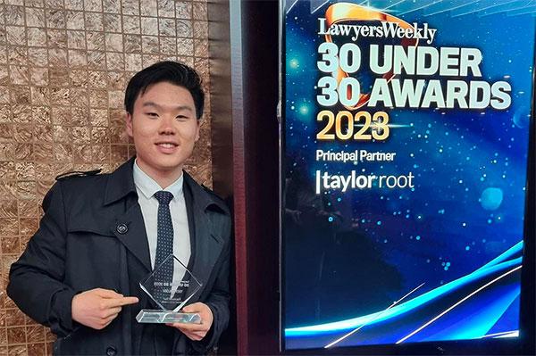 Raymond Sun standing by the sign for the 30 Under 30 Awards