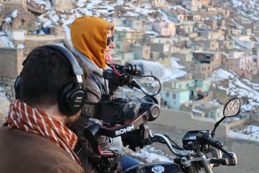 Jordan Bryon filming in Kabul, wearing a hoodie and sunglasses near a camera