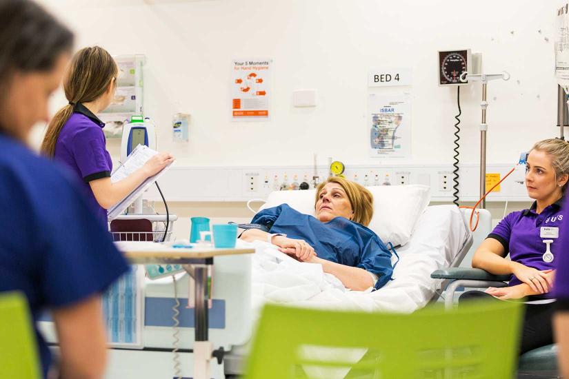 Patient in bed being cared for by nurses