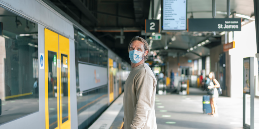 Man with COVID mask waiting for a train on the platform