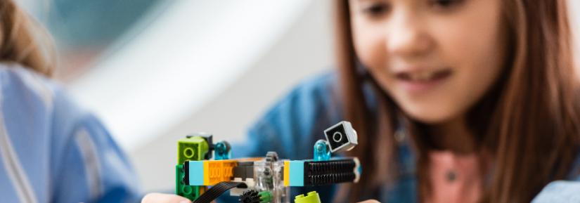 Girl plays with robotic lego. Adobe Stock