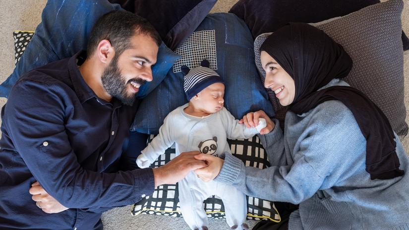 Parents lying down next to their newborn baby