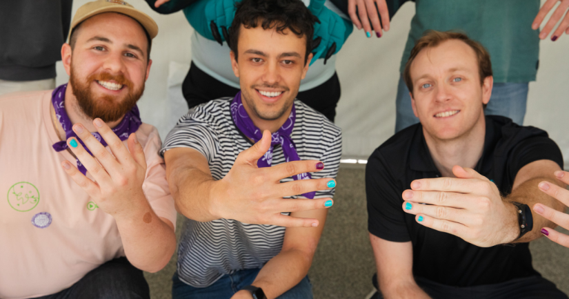 Three people holding painted nails to camera