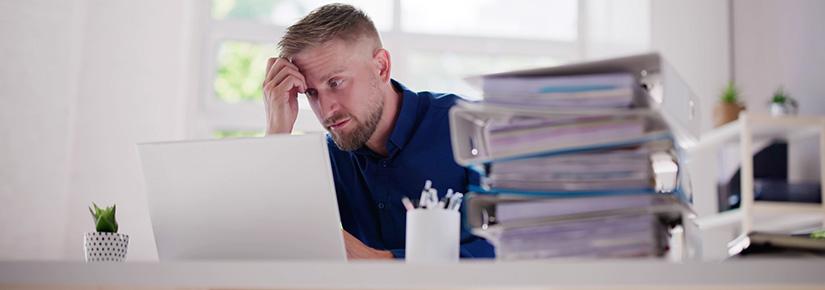 A man stares at a computer, looking tired