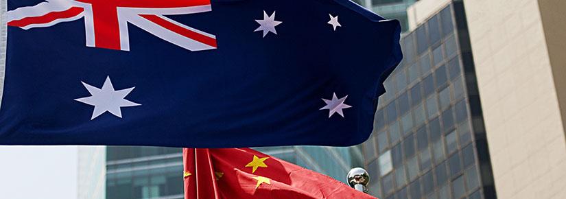 Stock picture of the Australian and Chinese flags flying with several high rise buildings in the background