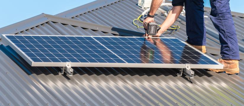 Stock picture of a workman insalling a rooftop solar panel