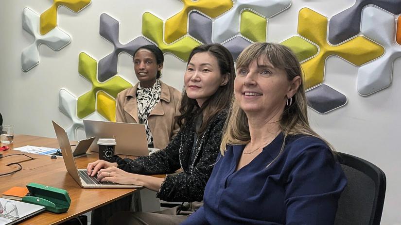 Dr Sarah Yeo and two other participants looking at presentation screen