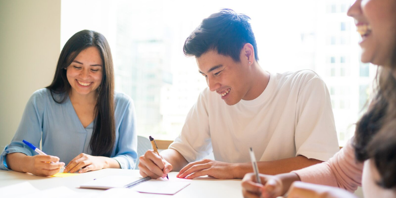 3 people writing notes on pieces of paper together