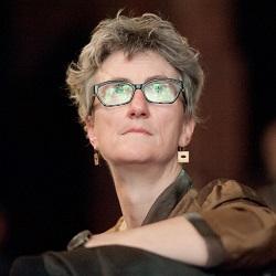 Photo of Professor Liz Harry looking up at a screen, which reflects on her glasses