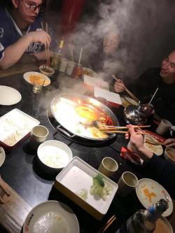 A group of people eating from a hotpot around a table