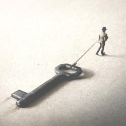 Miniature man dragging a big key
