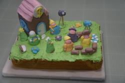 Cake decorated with gingerbread house, marshmallow figures and chocolate logs