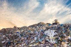 A tractor is moving waste on top of a pile of plastic rubbish