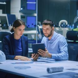 Two people in a lab looking at something on a tablet