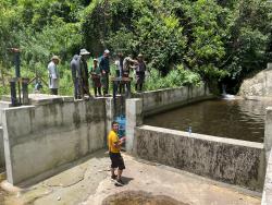 People standing around a man made water area in third world nation.