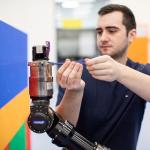 A man using a screwdriver on a robotic arm