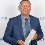 image of man holding an award and smiling at camera