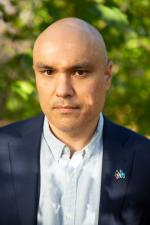 professional headshot of man in pale blue shirt and collared coat